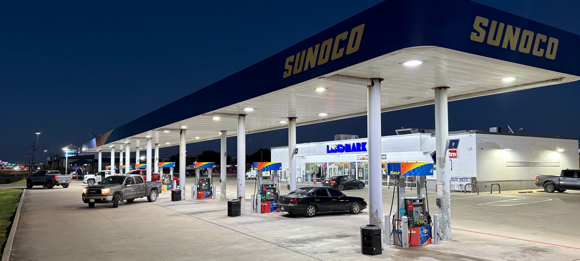 Landmark Sunoco at 2300 FM 365, Port Arthur at dusk: the lit Sunoco canopy over the fuel pumps, with the Landmark store behind