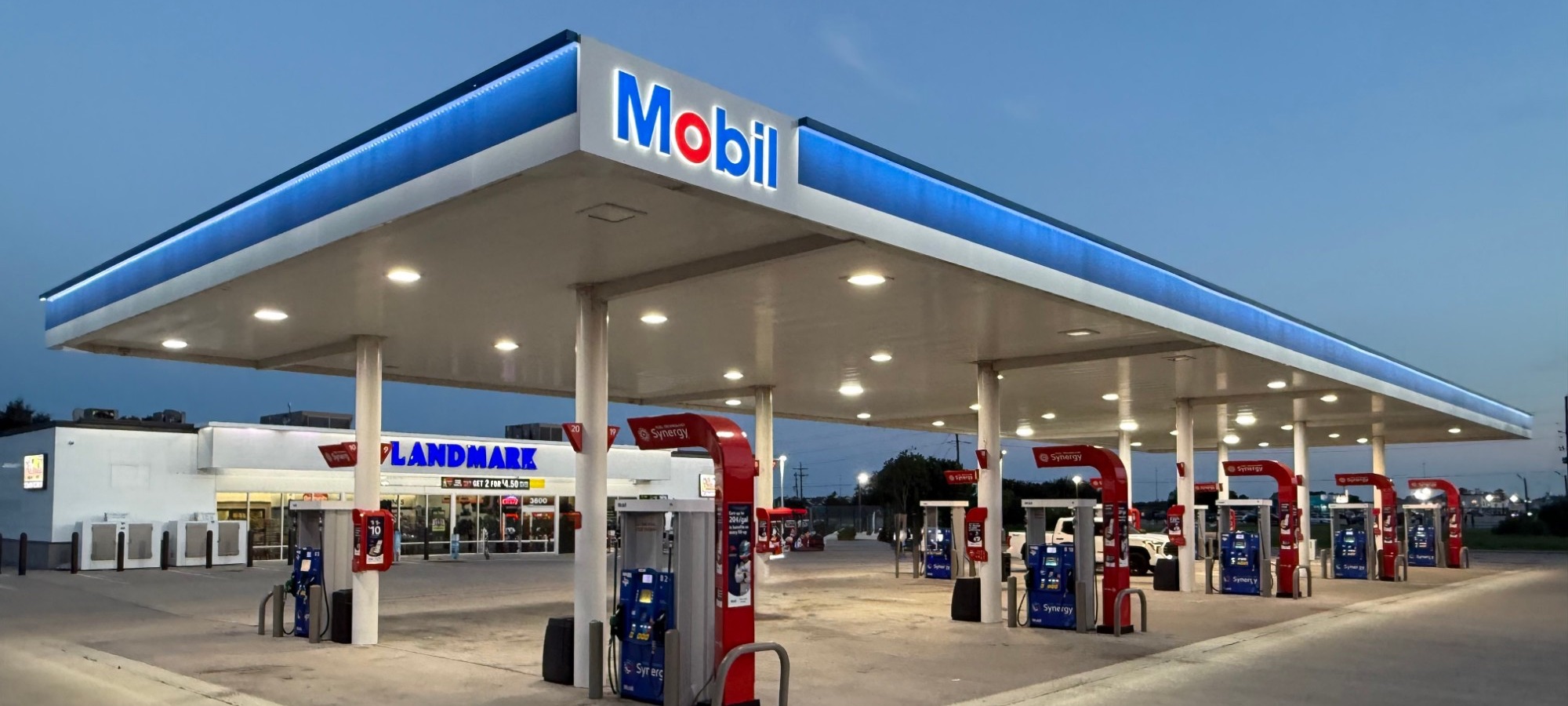 Landmark Mobil at 3600 Jimmy Johnson Blvd, Port Arthur, at dusk: the lit blue Mobil canopy over the fuel pumps, with the Landmark store behind